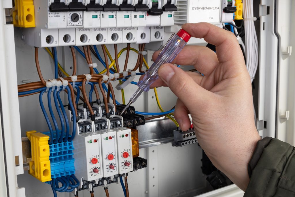 Technician,Using,Voltage,Tester,On,Wiring